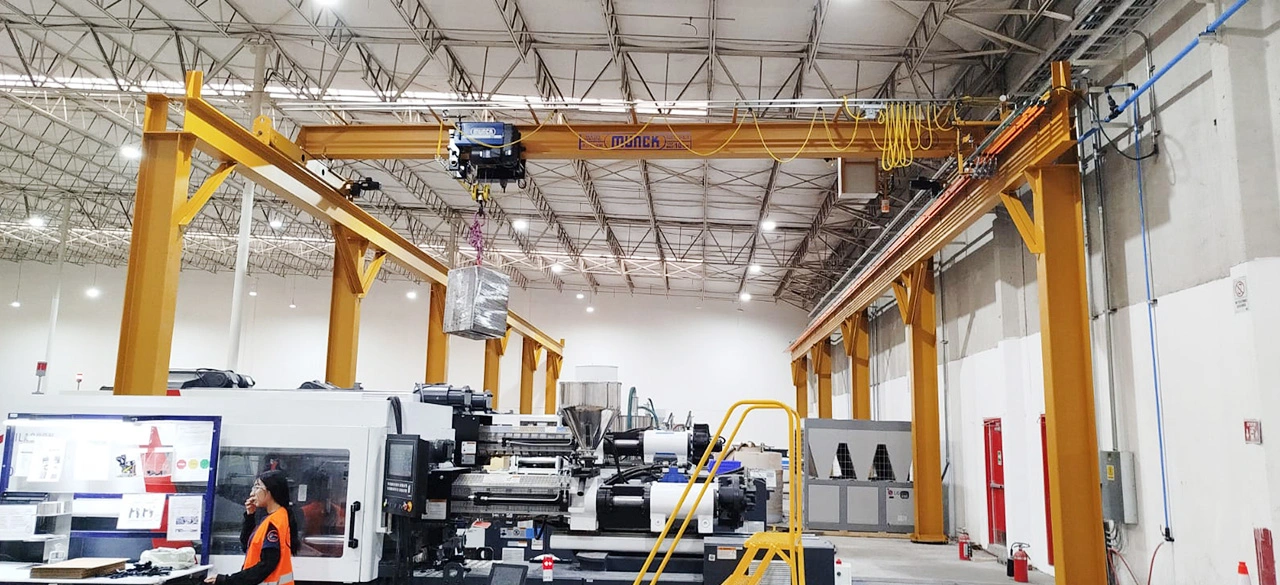 Nave industrial con grúas viajeras Munck sobre las máquinas de inyección y moldes en tránsito