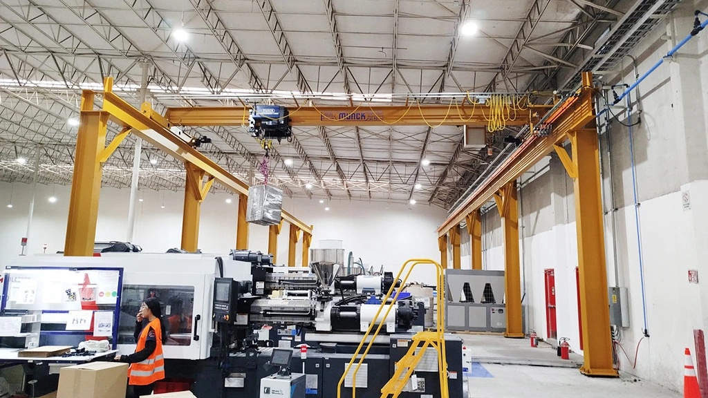 Grúa viajera birriel Munck elevando un molde de inyección dentro de la planta